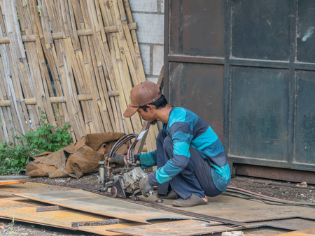 Jakarta,  Indonesia - February 20, 2018: Man repairing the engine of  motorcycle on the street of...