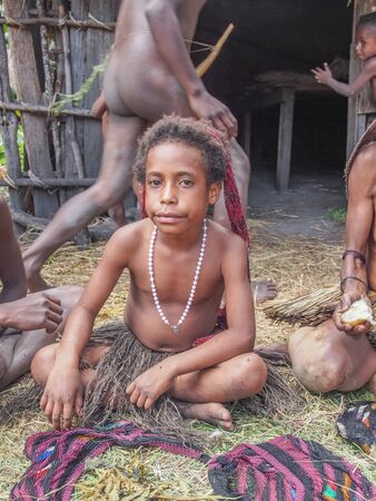 Wamena, Indonesia - January 23, 2015: Dani tribe girl selling local  handicraft in front of her wooden hutのeditorial素材
