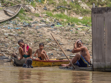 Iquitos, Peru - Sep 25, 2018: Family is taking a bath in the  Itaya River. A huge pollution can be seen in the background. Low water season of Amazon. BelÃ©n district of Iquitos, Peruのeditorial素材