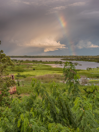 Iquitos, Peru- March 28, 2018: Sunset. View of a rusty boat, raibow and the Itaya river in center of  Iquitos, Loreto, Peru.  Amazonのeditorial素材
