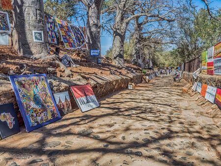 Goree, Senegal - February 2, 2019:  Typical art with pictures and blankets hanging from baobab trees on island of Goree. GorÃ©e. Dakar, Senegal. Africa.のeditorial素材