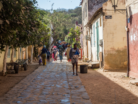 Goree, Senegal- February 2, 2019: Everyday life and street with a cobblestone road between colorful houses on the island of Goree. GorÃ©e. Dakar, Senegal. Africa.のeditorial素材
