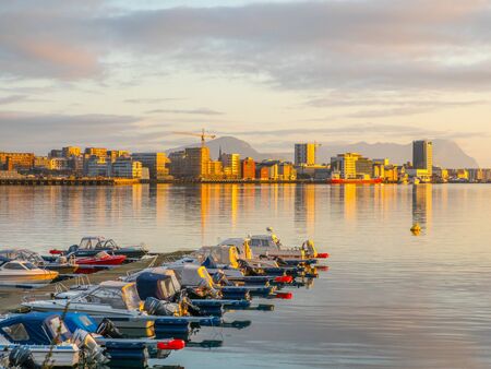 Ronvikleira, Bodo, Norway - August 18, 2019: View of the marina and sailing boats during the sunset with the city center and mountain in the background.  Nordland. Europe. Gate to Lofotenの写真素材