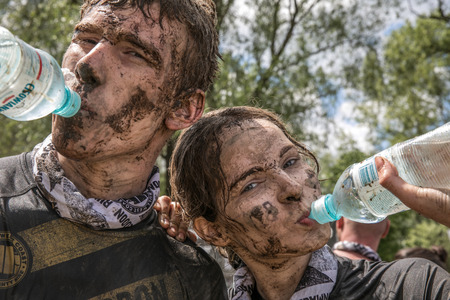 Warsaw, Poland - May 27, 2017: Portrait of young boy and girl  in dirty clothes drinking the water after extreme running with obstacle RUNMAGEDDONのeditorial素材