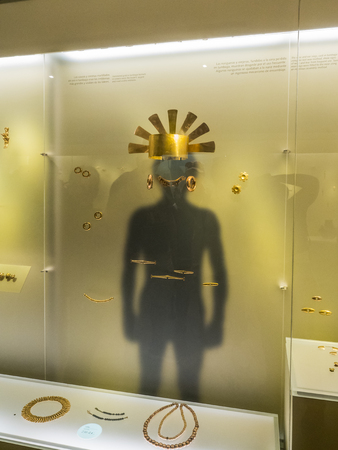 Bogota, Colombia - September 12, 2019: Exhibit  in Museum of Gold. Gold ornaments on the shadow of a person.のeditorial素材