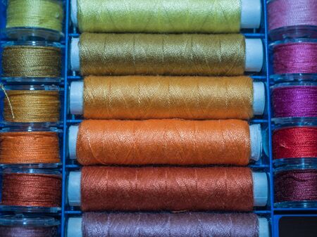 A lot of sewing colored thread. Thread reels. Colorful threads in the box. Texture of sewing...