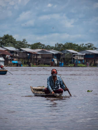 Belen, Peru- Dec 2019: Man fishing  from the small wooden boat between houses in the floodplain of the Itaya River, poorest part of Iquitos - BelÃ©n. Venice of Latin America. Iquitos, South America, Amazoniaのeditorial素材