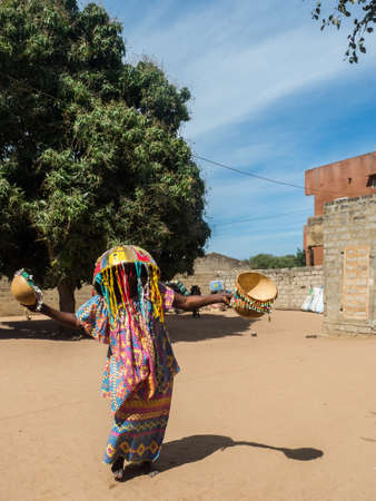 Senegal, Africa - January 2019: Senegalese woman in traditional dress called boubou and with a mask...