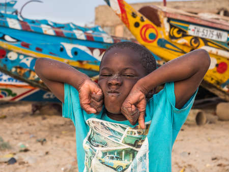 Senegal, Africa - January 24, 2019: Portrait of a black boy with a funny face. Colorful Senegalese...