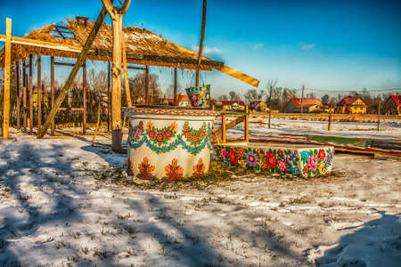 Zalipie, Poland - May 20, 2017: Hand-painted well and a metal bucket in a colorful village - Zalipie, an open-air museum in which all buildings and objects are decorated with a traditional floral motif. Winter time. Eastern Europe.のeditorial素材