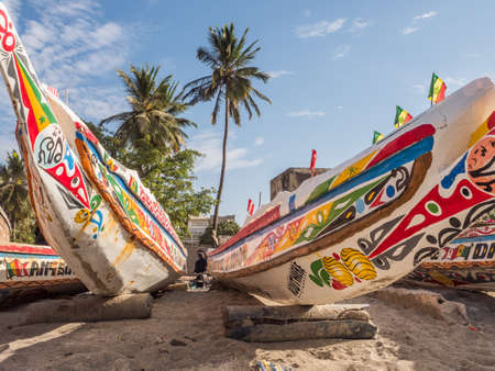 Senegal, Africa - January 24, 2019: Colorful wooden fisher boats standing on the sandy beach in...