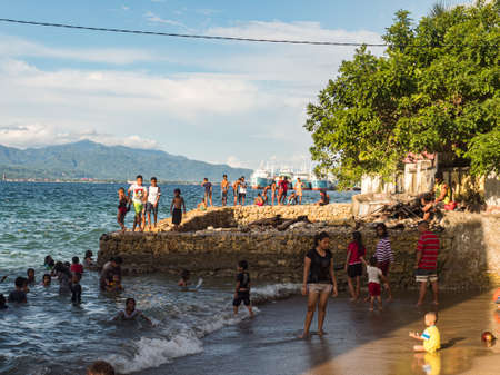 Ambon, Indonesia - February 2018: Many children play and swim in the bathing area at the city beach in the coastal town of Ambon. Ambon Island, Maluku Archipelago, (Moluccas) Indonesia. Asiaのeditorial素材