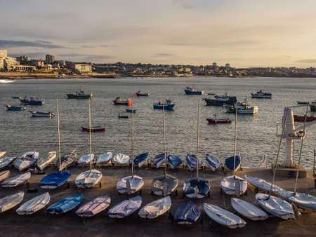 Cascais, Portugal - January 2019: Many fishing boat on the water and on the bank of the ocean during sunrise at the marina, and view for Cascais, Portugalのeditorial素材