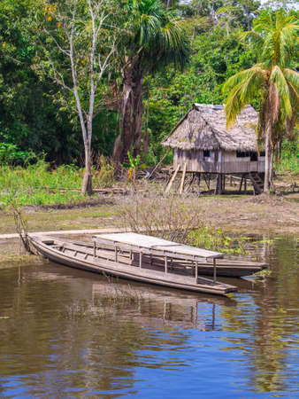 Amazon River, Peru - May 13, 2016: Wooden house on stilts with a roof made of palm leaves in a small village on the bank of the Amazon River, Amazonia. South America.のeditorial素材