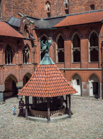 Malbork, Poland - May 22 2019: The well with the pelican's figure on the roof, a symbol of the Teutonic Order in the inner courtyard of the high castle. Medieval Teutonic castle in Malbork, (Marienburg) in Pomerania. Poland. Europeのeditorial素材