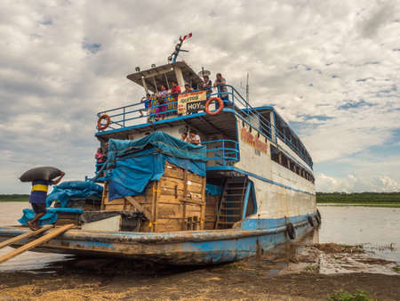 Amazon River, Peru - December 04, 2018: Cargo boat and the workers collecting the bags with rice.のeditorial素材
