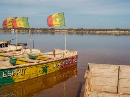 Lac Rose, Senegal - February 2019: Wooden boats with Senegalese flag on the shore of Lake Retba. Africaのeditorial素材