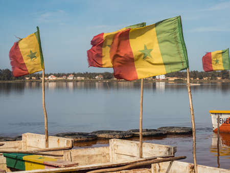 Lac Rose, Senegal - February 2019: Wooden boats with Senegalese flag on the shore of Lake Retba. Africaのeditorial素材