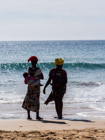 Dakar, Senegal - February 3, 2019: Senegalese women with children on their back on a sandy beach in Dakar. Africa.のeditorial素材
