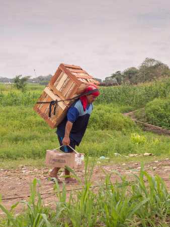 Tabatinga, Brazil - Sep, 2017: Peruvian man carrying on his back the big boxes with goods, bazaar near the port at Amazon river, South Americaのeditorial素材