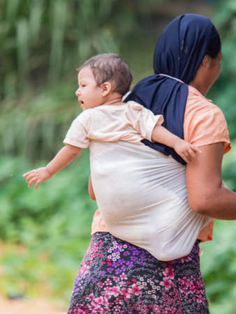 Amazonia, Peru - December 2017: A mother with a small child in a sling in a small village in the middle of the Amazon rainforest on the shore of the Amazon River. Amazon. South Americaのeditorial素材