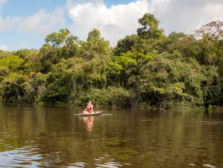 Laguna Onza, Brazil - December 2019: Caucasian woman swimming in the small wooden boat on the lagoon in Amazon rainforest. Amazon. Brazil. Latin Americaのeditorial素材