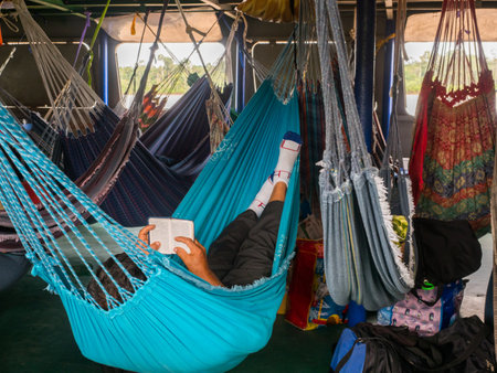 Amazon River, Peru - December 9, 2019: Man praying while laying on colorful hammocks on the cargo boat. South America. Amazonのeditorial素材
