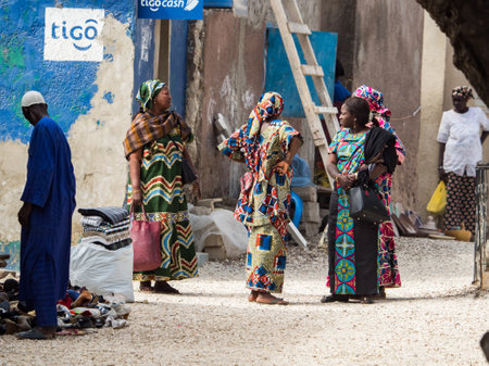 Joal-Fadiouth, Senegal - Jan, 2019: Women in a traditional costume called 'boubou' on the street of seashell island. Town and commune in the ThiÃ¨s Region, Petite CÃ´te of Senegal. Africa.のeditorial素材