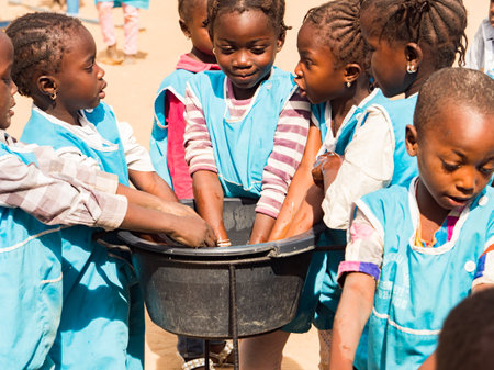 Senegal, Africa - January 2019: African children in uniform wash their hands before eating during their break from school.のeditorial素材