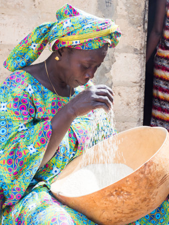 Senegal, Africa - Jan, 2019: Portrait of a beautiful Senegalese woman in a traditional costume called 'boubou' with a bowl of riceのeditorial素材