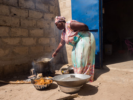 Senegal, Africa - Jan, 2019: Senegalese woman in a traditional costume called 'boubou' cooking the meal in the african home.のeditorial素材