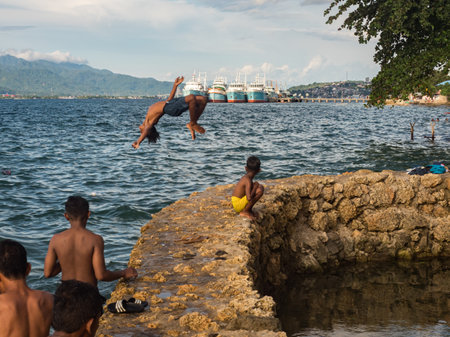 Ambon, Indonesia - February 2018: Many children play and swim in the bathing area at the city beach in the coastal town of Ambon. Ambon Island, Maluku Archipelago, (Moluccas) Indonesia. Asiaのeditorial素材