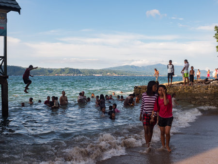 Ambon, Indonesia - February 2018: Many children play and swim in the bathing area at the city beach in the coastal town of Ambon. Ambon Island, Maluku Archipelago, (Moluccas) Indonesia. Asiaのeditorial素材