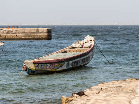 Nianing, Senegal - January 24, 2019: Colorful wooden fishing boats bouncing on the waves anchored far from the beach. Africaのeditorial素材