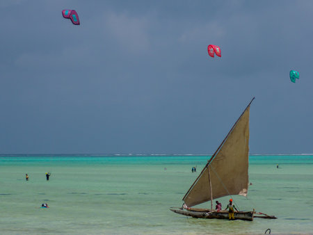 Zanzibar, Tanzania - Jan, 2021: A traditional sailing dhow ship with a huge white sail on the blue...