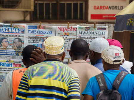 Stone Town, Zanzibar - Feb 2021: A group of African men reads paper newspapers hung on a Tanzania wall. Covid time in Africa.のeditorial素材