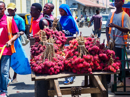Zanzibar, Tanzania - February 2021: Lots of red lychees sold directly from a wooden cart in the street of Africa. Other famous names: lychee, longan, pulasan, mamoncillo, rambutanのeditorial素材