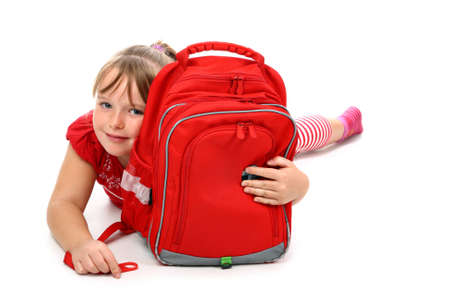 Happy girl lying on floor hugging red school bag smiling isolated on whiteの写真素材