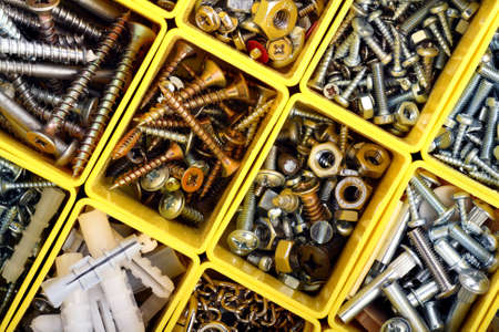 Screws, bolts, nuts and other carpenter stuff in a yellow plastic toolboxの写真素材