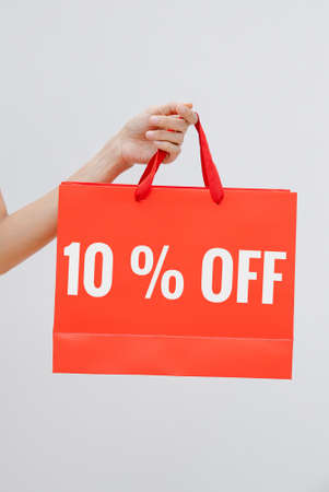 Woman holding red shopping bag with 10 percent off sign on white backgroundの写真素材