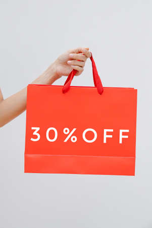 Woman holding red shopping bag with 50 percent off discount on white backgroundの写真素材