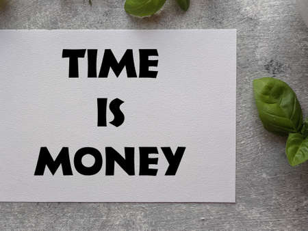 Time is money text on white paper with green leaves on wooden backgroundの写真素材