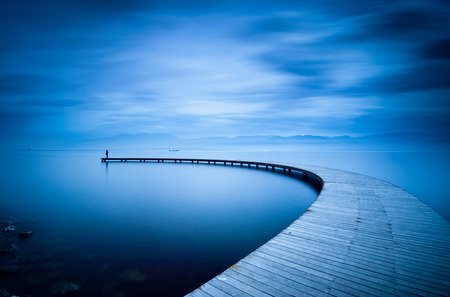 Young man looking to sea on curved jetty.の写真素材