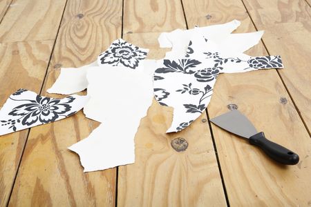 Stripped wallpaper and wallpaper stripper on the floorの写真素材