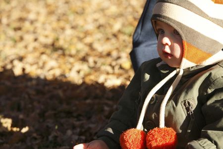 Preschooler in winter clothes  sitting in the parkの写真素材
