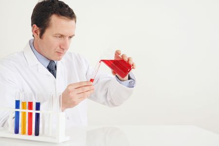 Man pouring liquid from beaker into test tubeの写真素材