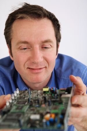 Man examining a computer circuit boardの写真素材