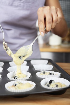 Woman filling up the muffin liners on baking tray