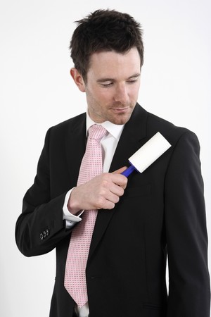 Businessman using lint roller on his coatの写真素材