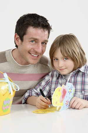 Man and boy smiling at the camera, boy holding an Easter cardの写真素材